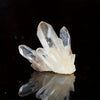 A cluster of clear quartz crystals reflecting on a dark surface.
