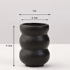 A matte black ceramic vase with a stacked, rounded design shown against a white background.