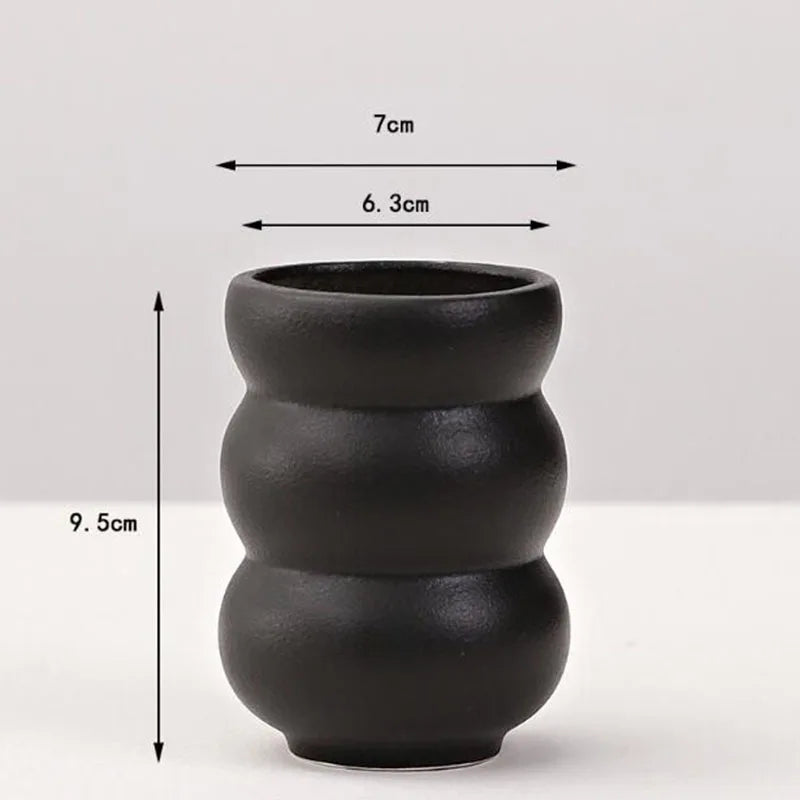 A matte black ceramic vase with a stacked, rounded design shown against a white background.