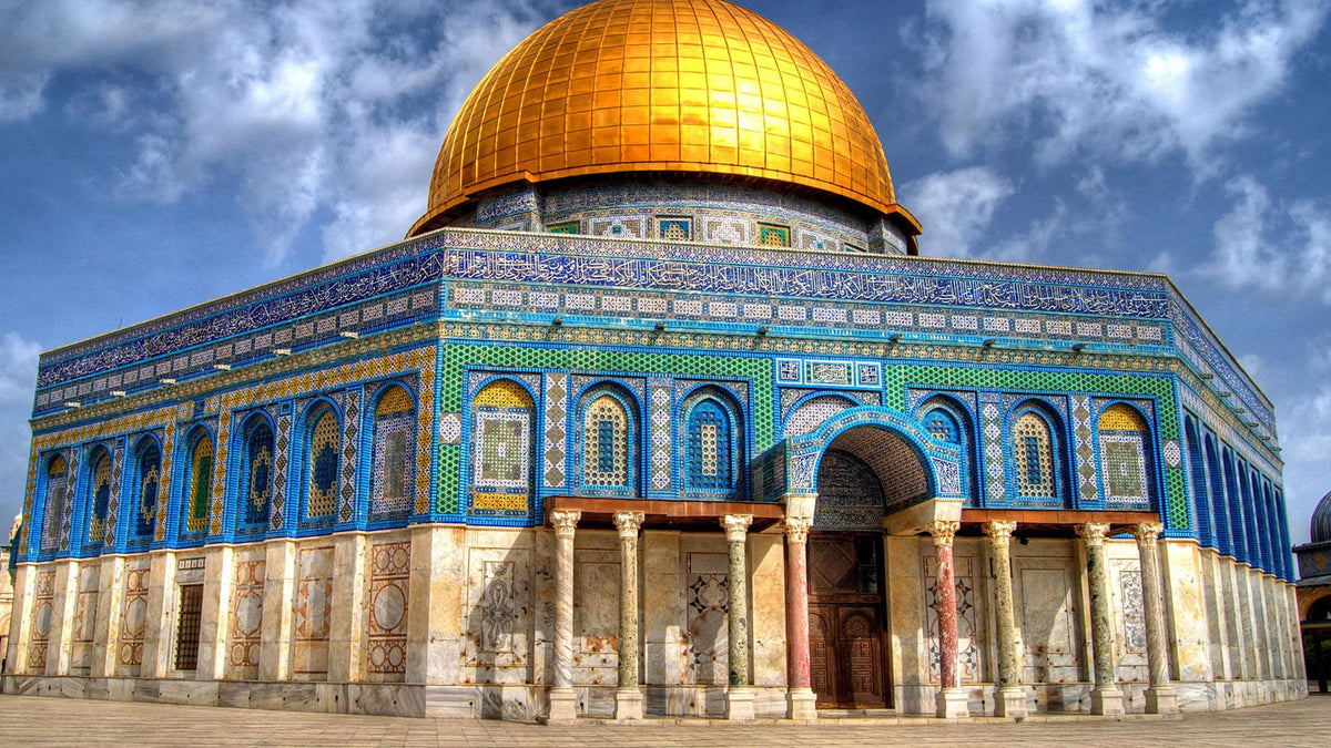 A golden dome mosque structure with blue and white tilework under a cloudy sky.