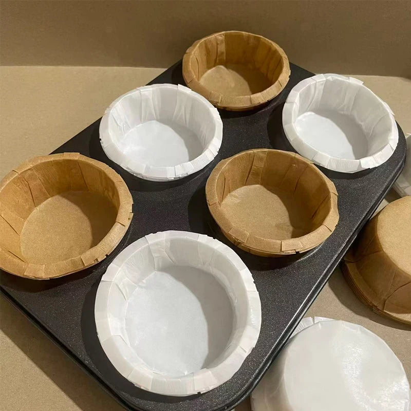 A collection of fluted paper cups in white and kraft brown colors arranged on a dark tray.