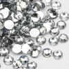 A close-up view of many clear, round flatback resin rhinestones scattered on a white background.