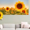 A vibrant painting of a field of sunflowers displayed above a light green wall.