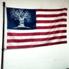 A large flag featuring a silhouette of a tree on a blue field and red and white stripes.