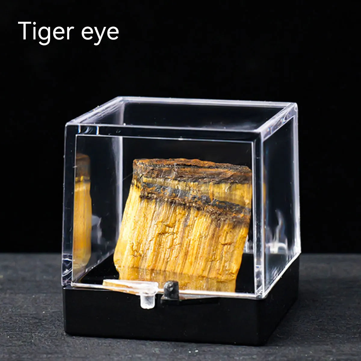 A natural tiger eye rough stone specimen displayed inside a clear glass box.