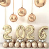 A display of large champagne gold foil number balloons spelling out 2026 for party decor.