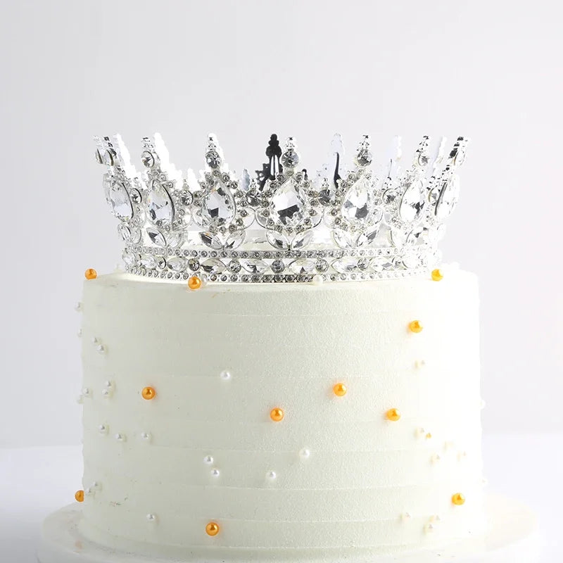 Gâteau à étages blanc décoré d'accents dorés et surmonté d'une couronne élégante en cristal et métal.