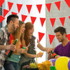 A group of people celebrating with a red triangle bunting flag garland in the background.