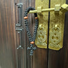 A handmade black prayer rope with a cross charm is displayed on a brass door hanger.