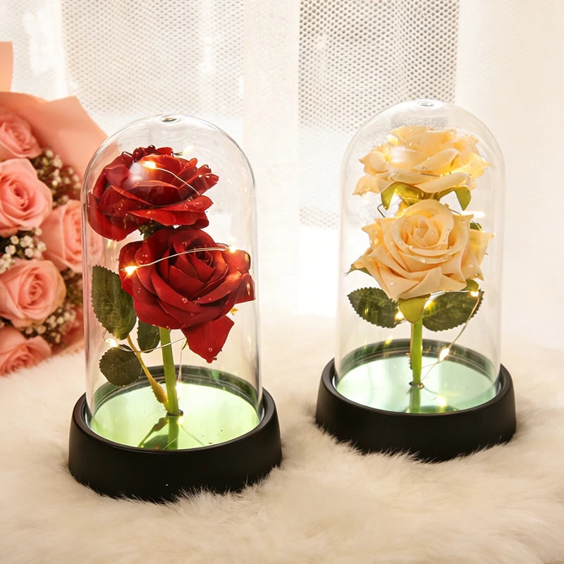 A glass dome containing a red rose and a glass dome containing a yellow rose, both illuminated by an LED light.