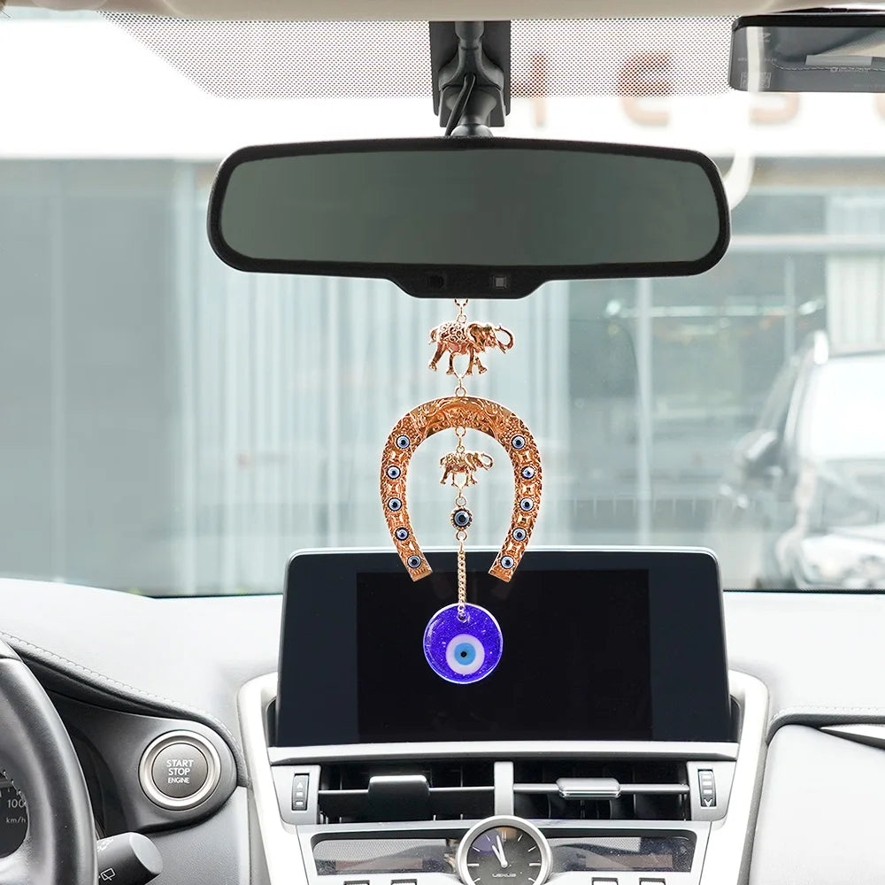 An elephant charm amulet hanging from a horseshoe on a wall display inside a car