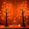A glowing Halloween birch tree lamp featuring skeletal figures and LED lights on a wooden surface.