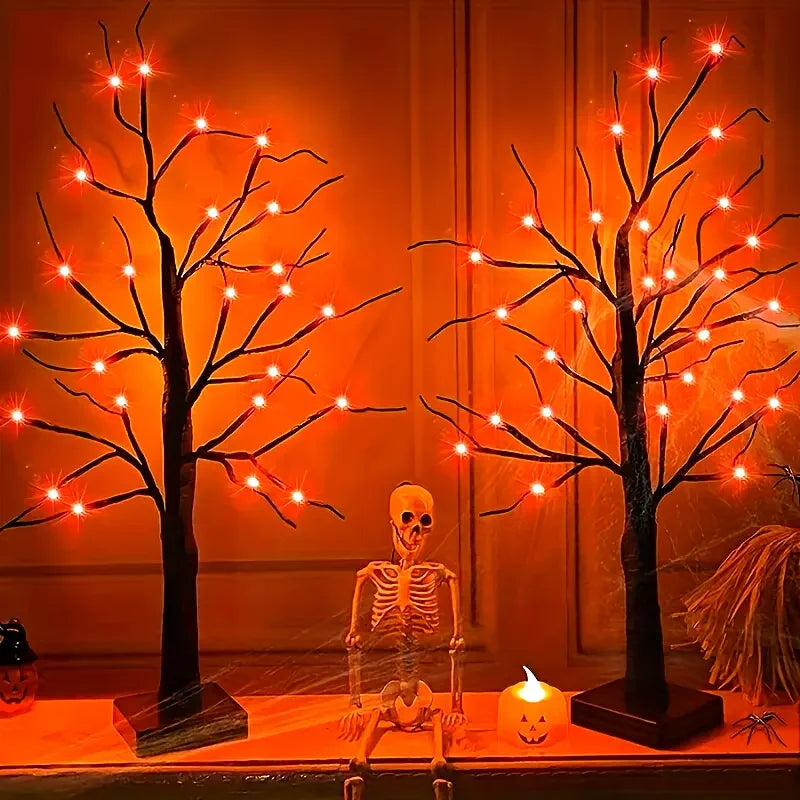 A glowing Halloween birch tree lamp featuring skeletal figures and LED lights on a wooden surface.