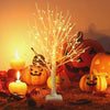 An LED birch tree decorative light illuminated in a Halloween-themed setting with pumpkins and glowing candles.