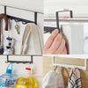 A close-up of a black iron door and wall organizer rack with hooks, showing installation on a white cabinet and wood surface.