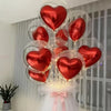 A set of red heart-shaped foil balloons and clear bubble balloons tied with pink ribbons for decoration.