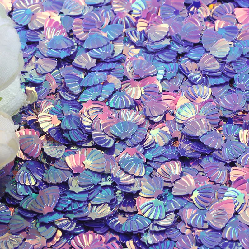 Glittery purple and pink seashell confetti scattered on a surface.
