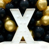 A large white marquee letter X is displayed in front of a backdrop of gold and black balloons for party decor.