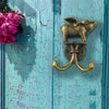 A brass decorative metal wall hook shaped like a ram or goat mounted on a wooden surface.