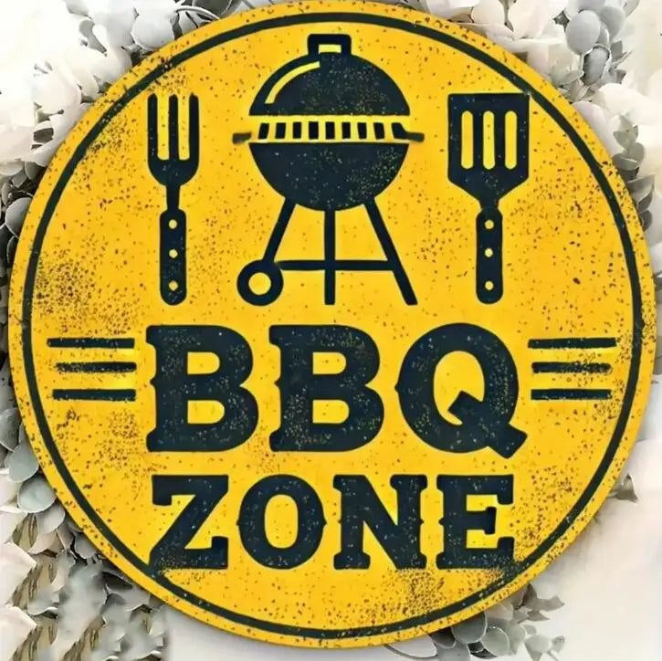 Panneau rond jaune avec texte noir indiquant BBQ ZONE, entouré de feuilles décoratives blanches.