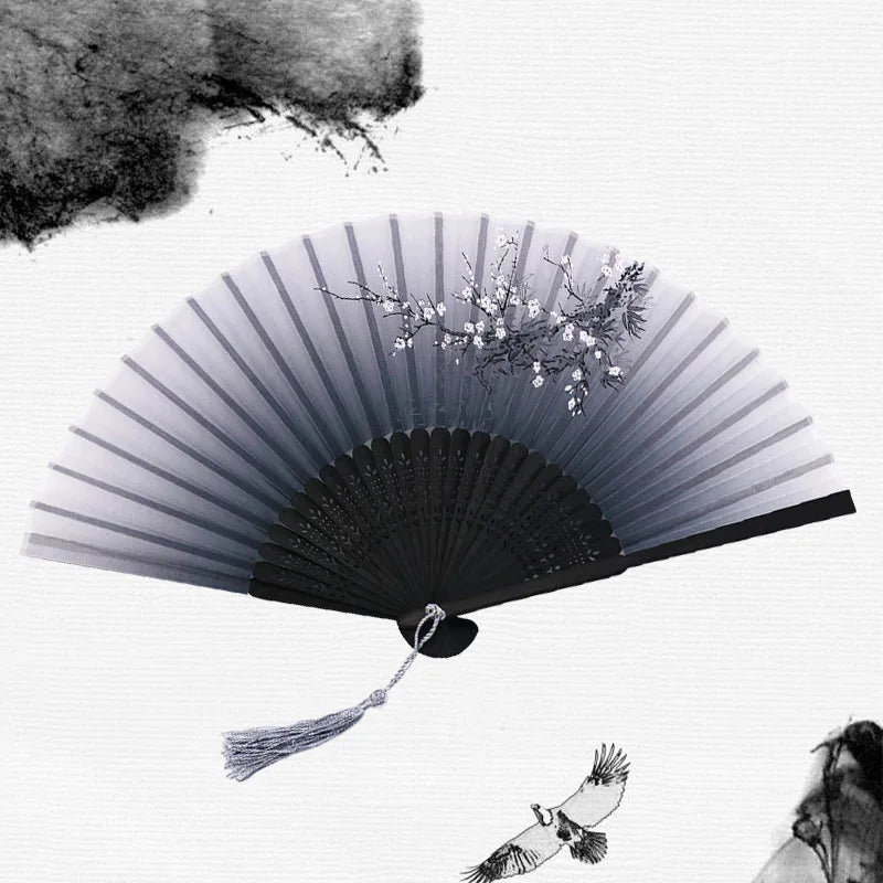 A black and white image of a vintage bamboo folding hand fan with delicate floral accents.