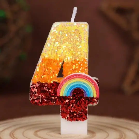 A candle shaped like the number 4 covered in gold glitter sits next to a rainbow sequined candle.