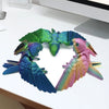A set of three articulated 3D printed parrot figurines with movable wings in shades of green, blue, and pink.