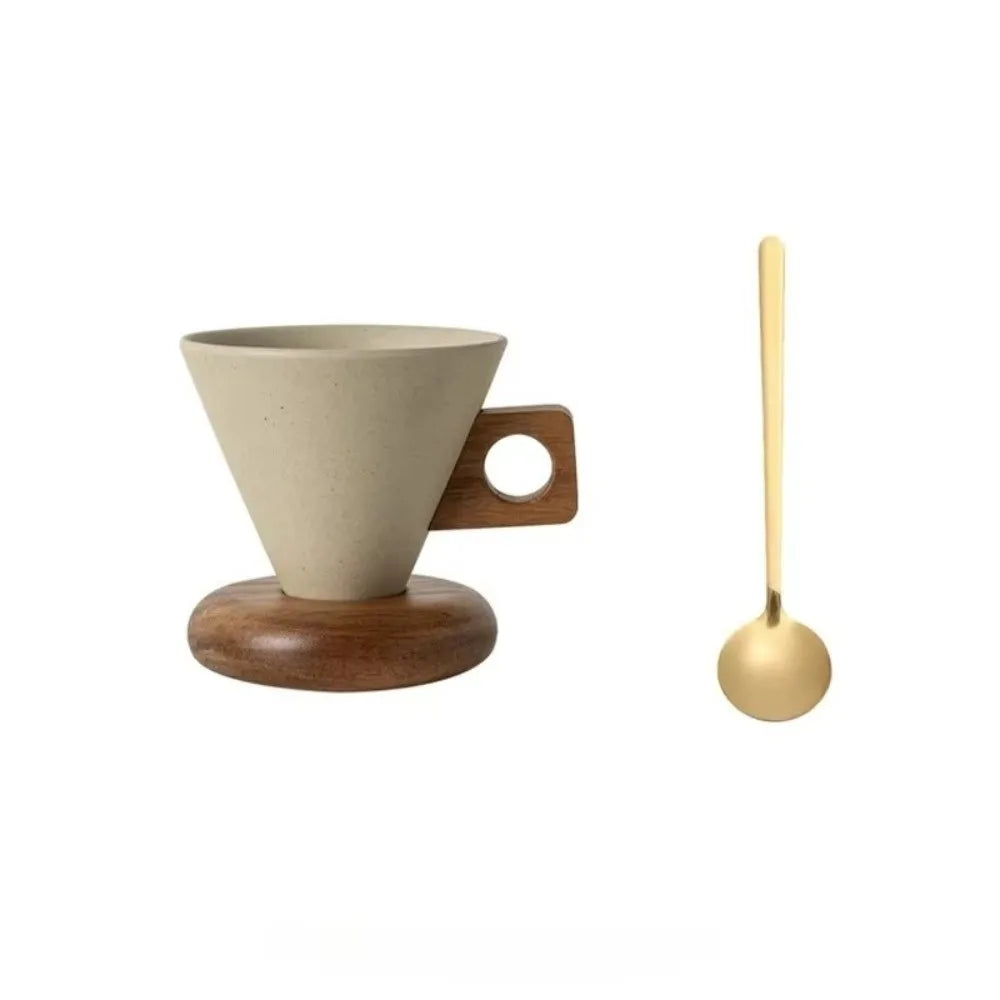 A ceramic coffee mug with a light beige interior and exterior sits on a round wooden base, next to a gold-colored spoon.
