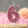 Pink glitter number six candle with a silver crown topper