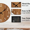 A minimalist wooden wall clock with black metal hands and large numbers displayed on a light wood surface.