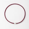 A handmade red string bracelet with a gold plated clasp laid flat against a white background.