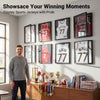 A man stands in a room displaying several framed sports jerseys on the wall.