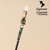 A natural clear quartz zodiac crystal wand with gold accents and a green bead, used for meditation and healing.