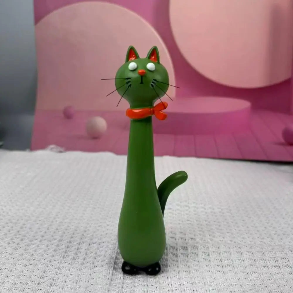 A green cat-shaped resin vase with orange accents is displayed on a white surface against a pink background.