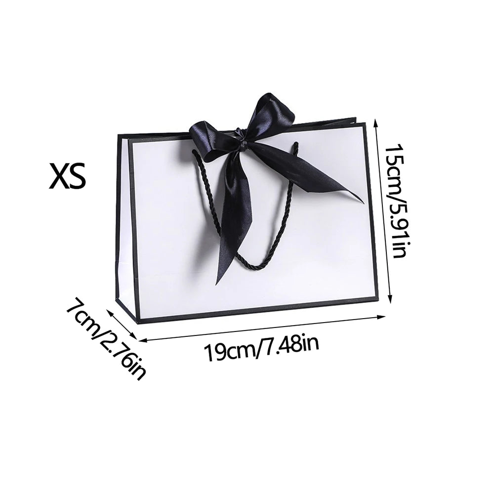 A rectangular black and white gift bag with a black ribbon bow shown next to dimension markings.