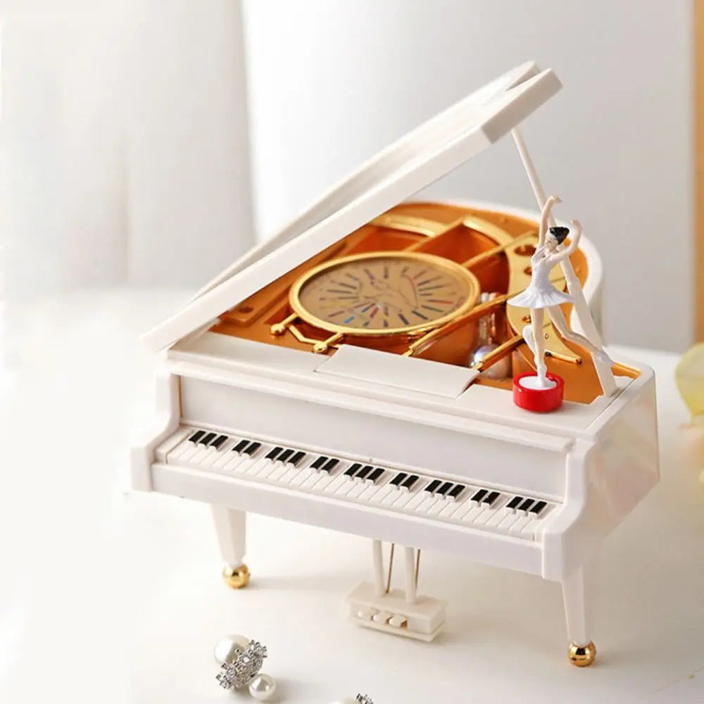 A white hand-crank music box with an open lid revealing a ballerina figure and a spinning mechanism.
