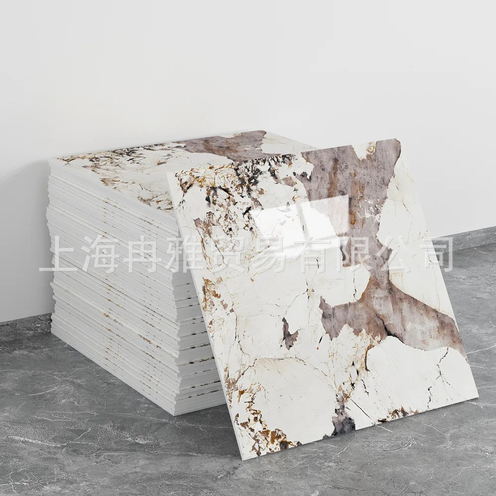 A stack of white faux marble self-adhesive wall tiles with brown veining displayed on a gray floor.
