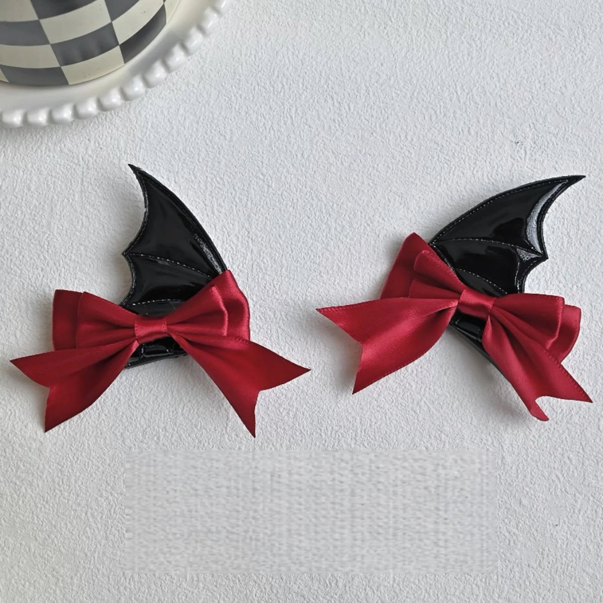 A pair of black devil horn and bat wing hair clips in deep red satin ribbon.