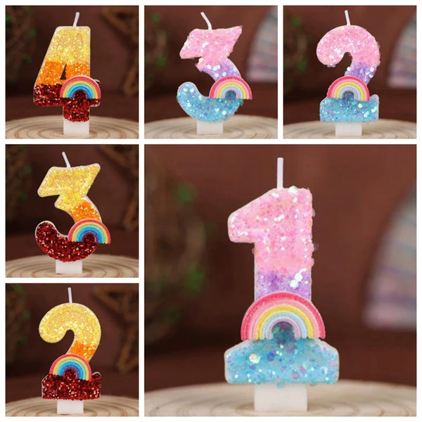 A set of rainbow sequined number candles shaped like 1, 3, 5, and 7 displayed on a wooden surface.