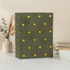 A dark olive green laminated photo album with gold heart patterns resting on a white surface.