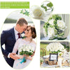 A bride and groom holding a white rose bouquet with green foliage for wedding parties and décor.
