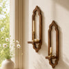 A rustic wooden arch wall shelf holds a white candle and a small bowl on a light-colored wall.