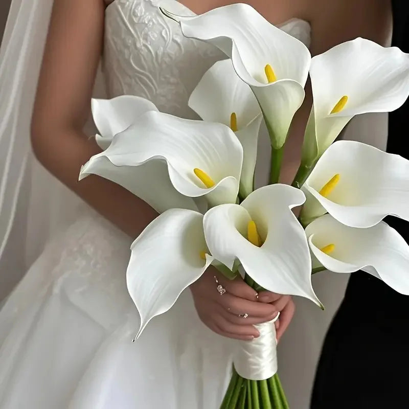A bride holds a bouquet of five white calla lily stems with yellow centers.