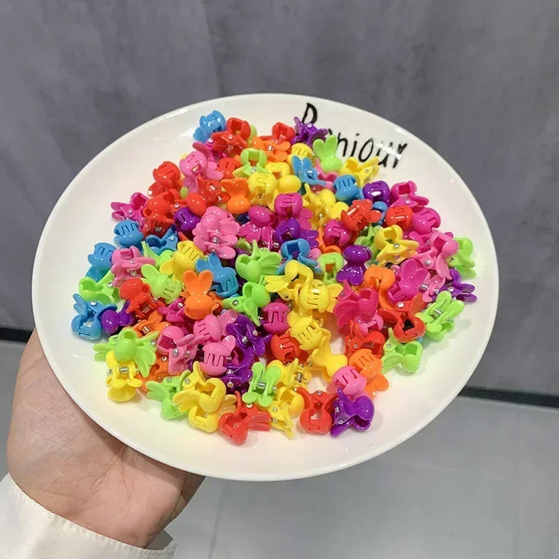 A pile of colorful flower and star hair claw clips for kids displayed on a white plate.