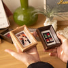 A hand holds a small wooden photo frame containing a vintage-style photograph.