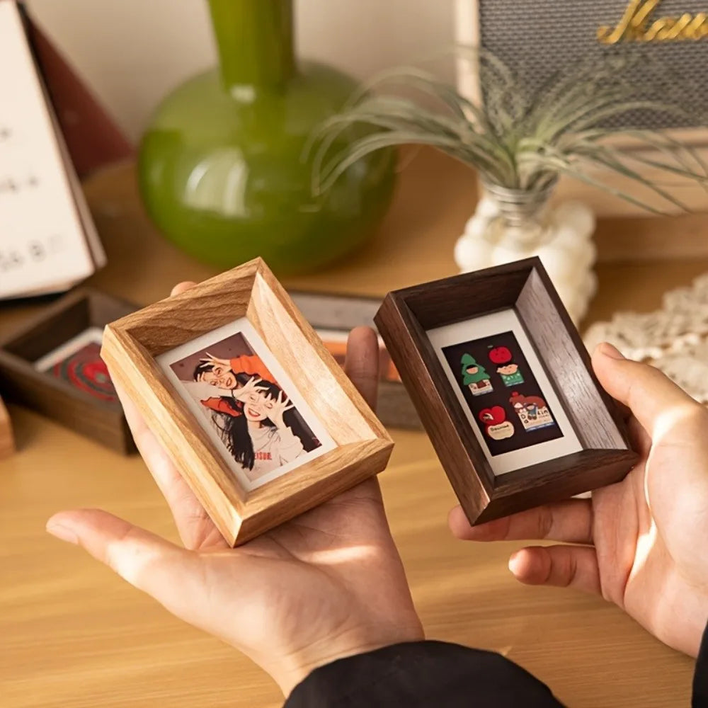 A hand holds a small wooden photo frame containing a vintage-style photograph.