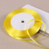 A roll of bright yellow satin ribbon on a white spool, ready for gift wrapping or crafts.