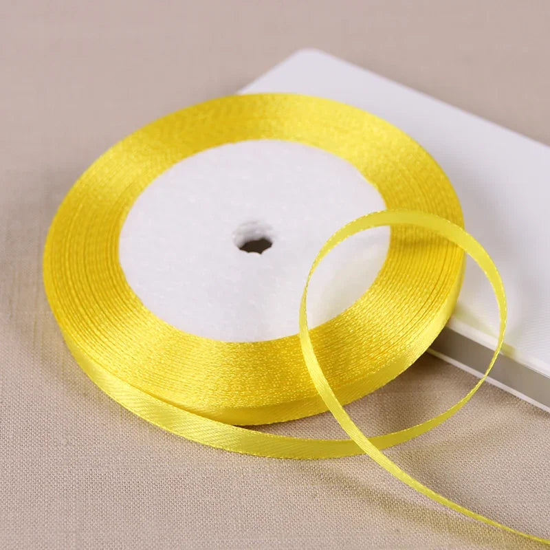 A roll of bright yellow satin ribbon on a white spool, ready for gift wrapping or crafts.
