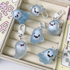 A collection of light blue ghost-shaped glow-in-the-dark keychains displayed in a rectangular box.