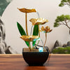 A golden tabletop fountain featuring green leaves and water spouts set in a dark bowl.